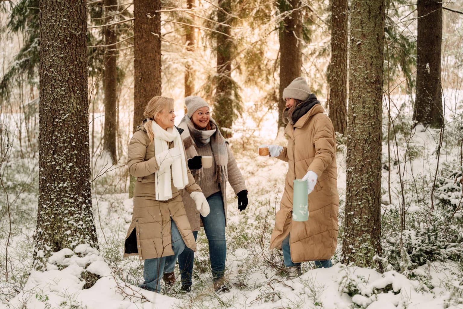 Mind Teamin ammattilaiset lumisessa metsässä lämpimissä talvivaatteissa, juomassa lämmintä juomaa